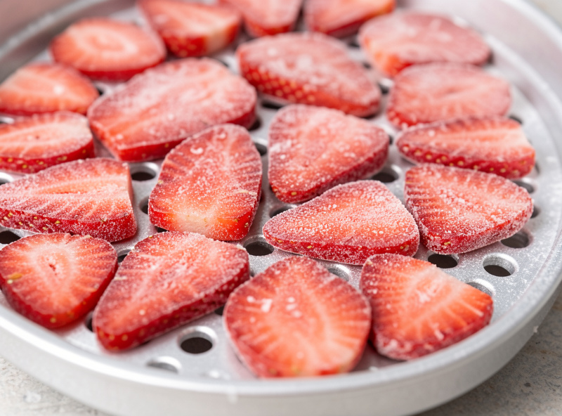 A tray of pre-frozen sliced strawberries arranged in a single even layer before going into a home freeze dryer